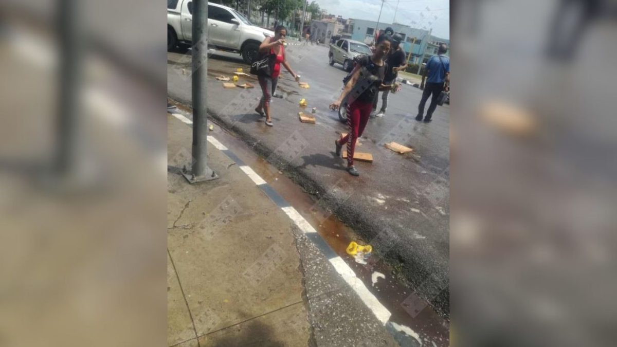 Vecinos de Santiago de Cuba recogen latas de malta caídas desde un camión