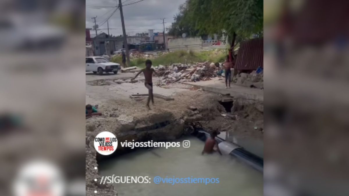 Niños juegan en un peligroso socavón lleno de agua en La Habana