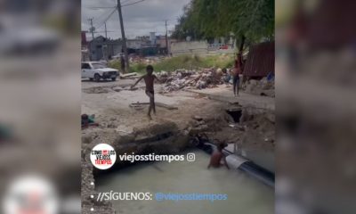 Niños juegan en un peligroso socavón lleno de agua en La Habana